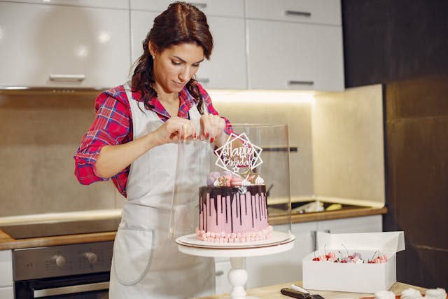 Una mujer decorando una tarta de cumpleaños, receptes casolanes